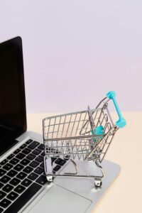 pexels-photo-5632382-5632382 Mini shopping cart on a laptop symbolizes online shopping and e-commerce themes.